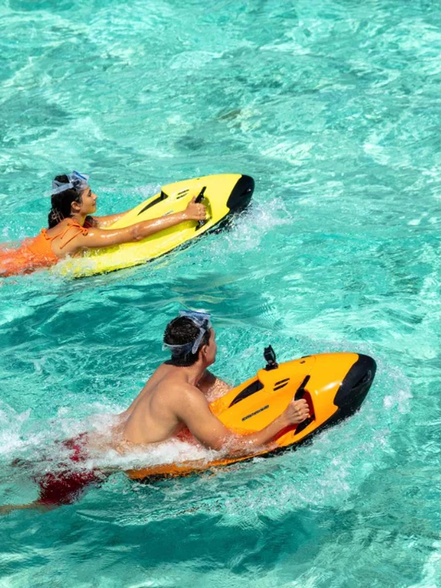 Two guests riding sea-bob underwater scooters through Kandima's clear lagoon
