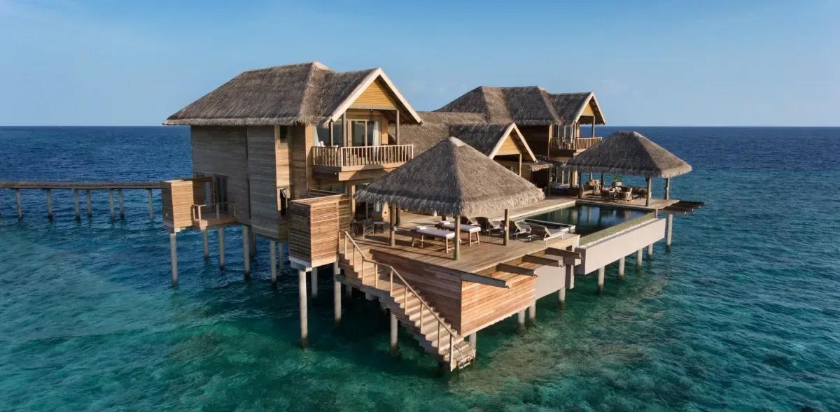 Golden-hour aerial view of the Vakkaru Over Water Residence's pavilions and pool at the reef's edge