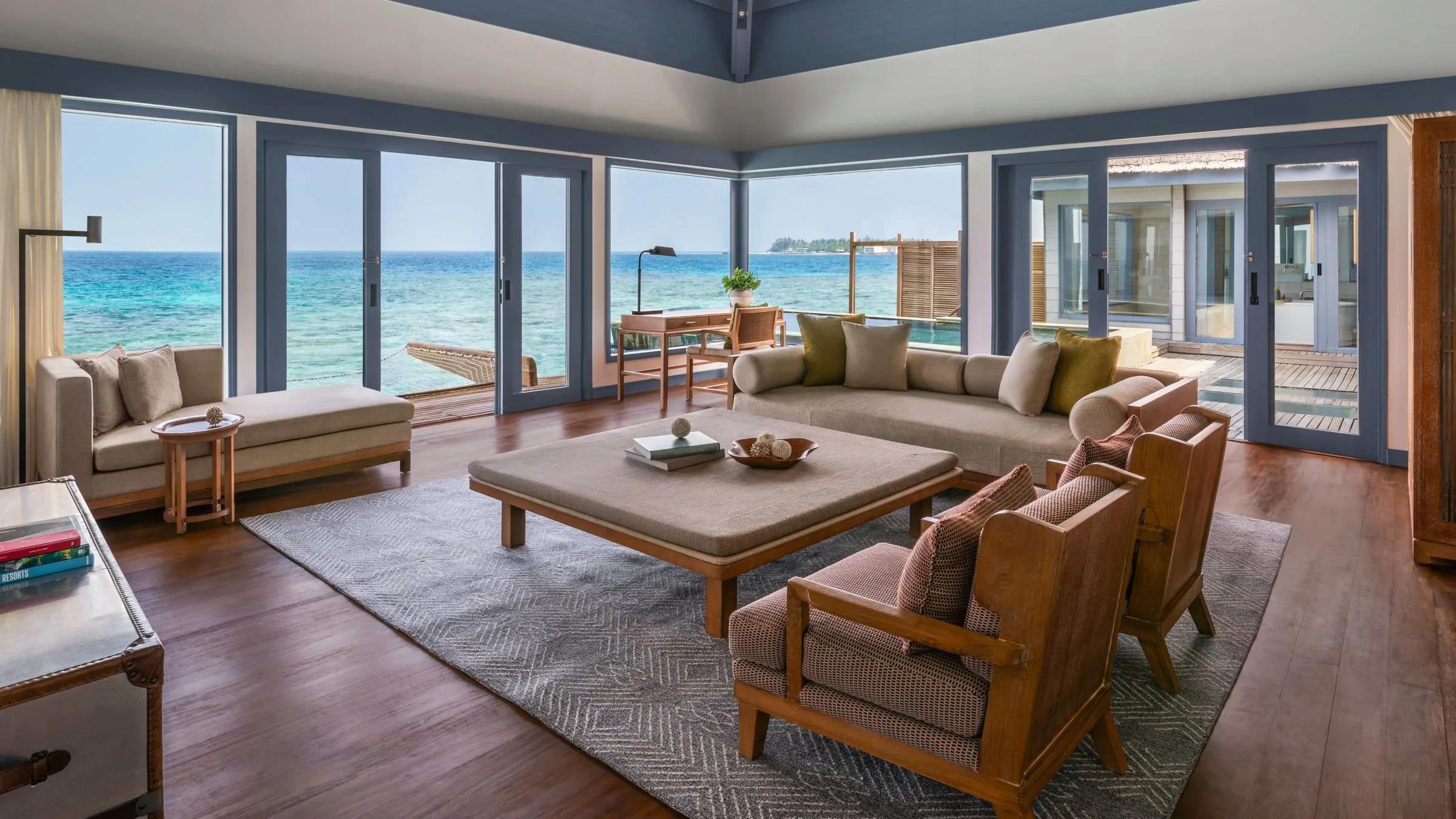 The living area of an Overwater Villa, glass doors open toward the lagoon