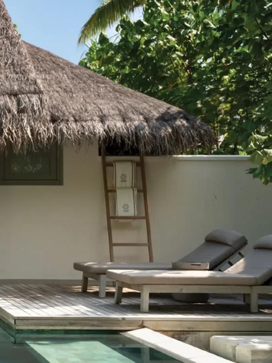 Exterior of a One Bedroom Beach Pool Residence, its thatched roof opening onto a private pool and an outdoor soaking tub