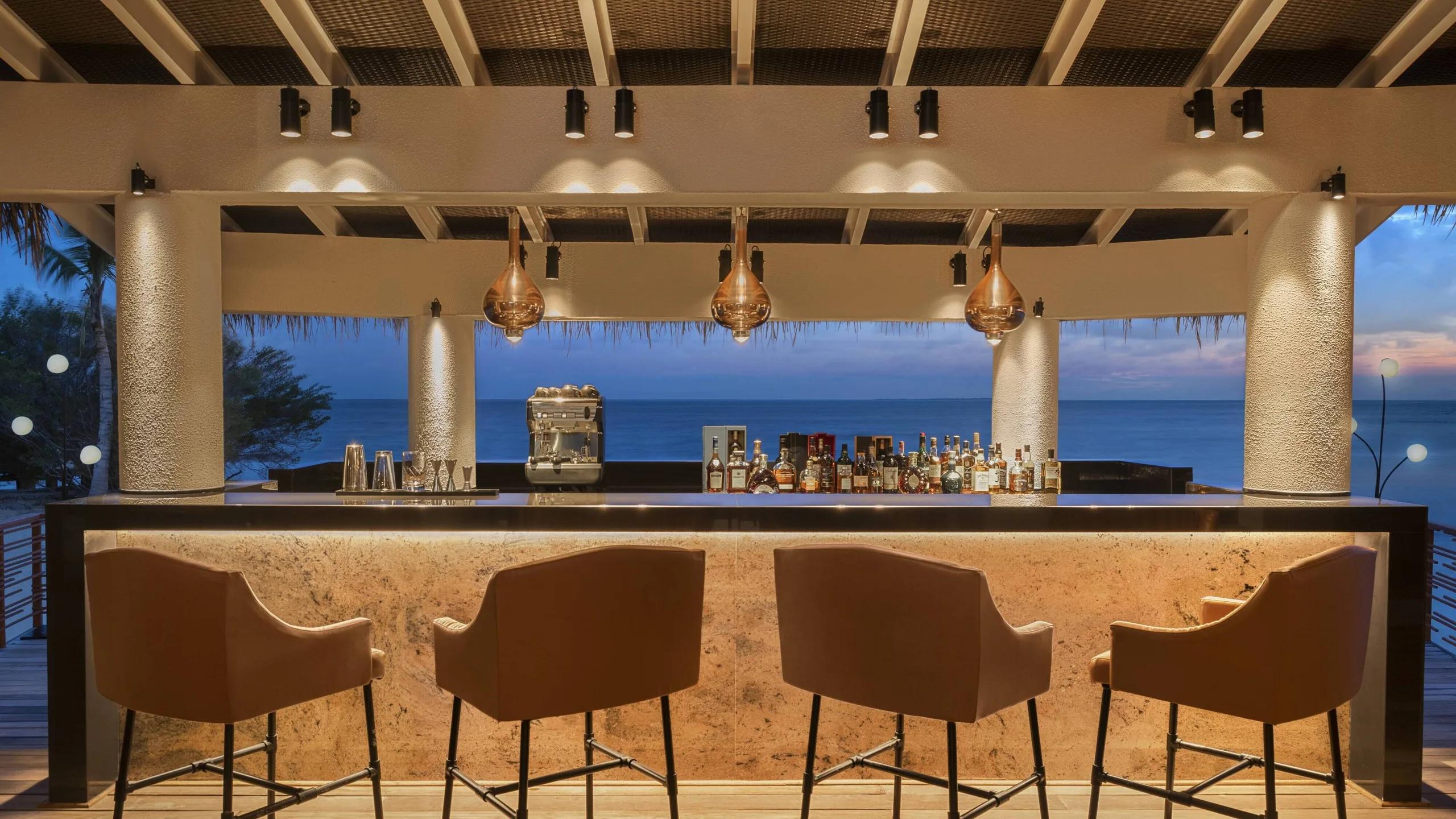 The bar at Wabi Sabi, copper pendant lights over the counter and the sea beyond