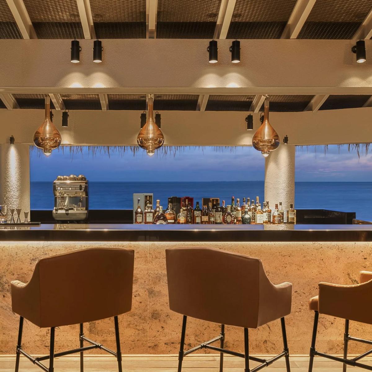 The bar at Wabi Sabi, copper pendant lights over the counter and the sea beyond