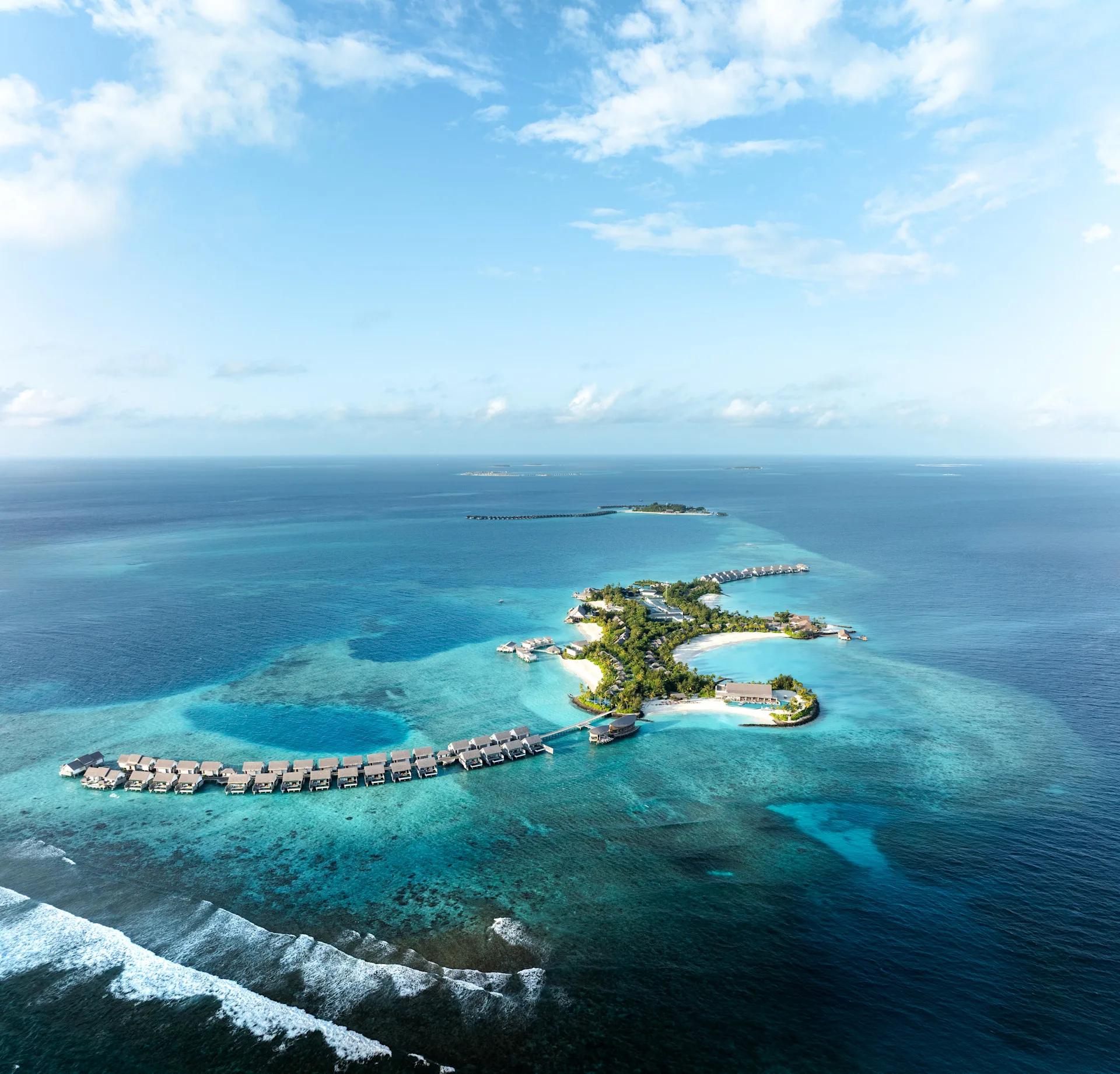 An aerial view of the whole island at Hilton Maldives Amingiri, reef and lagoon surrounding the resort
