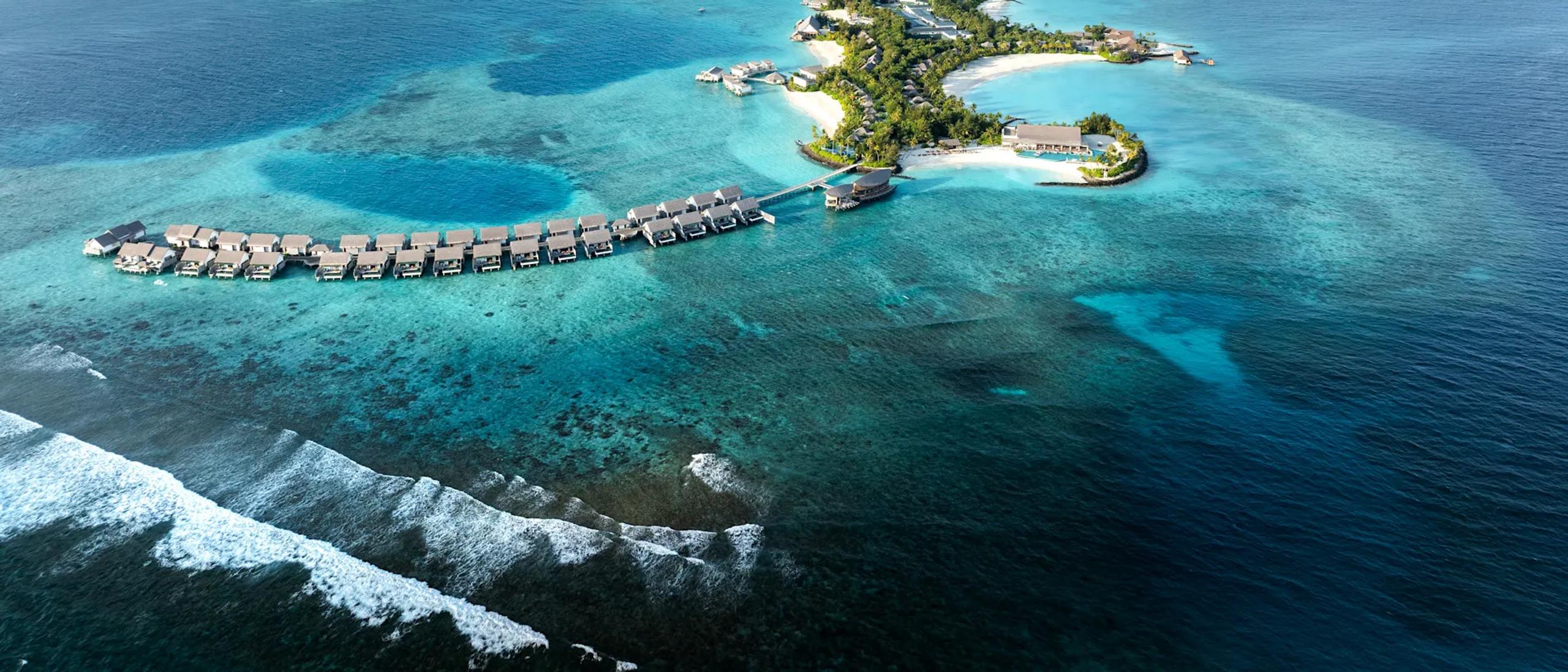 An aerial view of the whole island at Hilton Maldives Amingiri, reef and lagoon surrounding the resort
