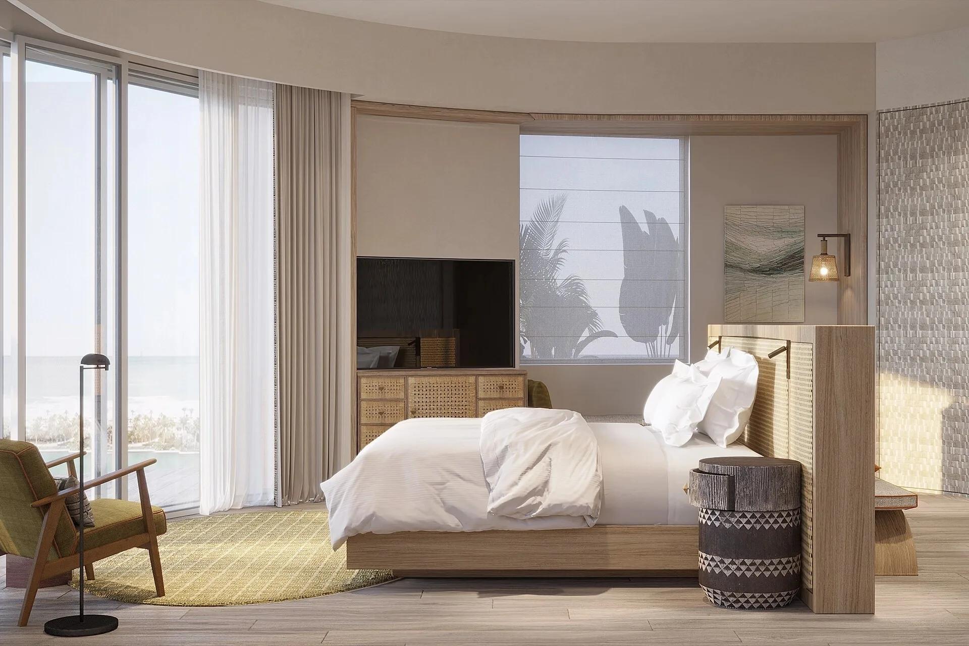 A Grand Lagoon Villa bedroom with floor-to-ceiling glass doors opening onto a private terrace and the lagoon beyond