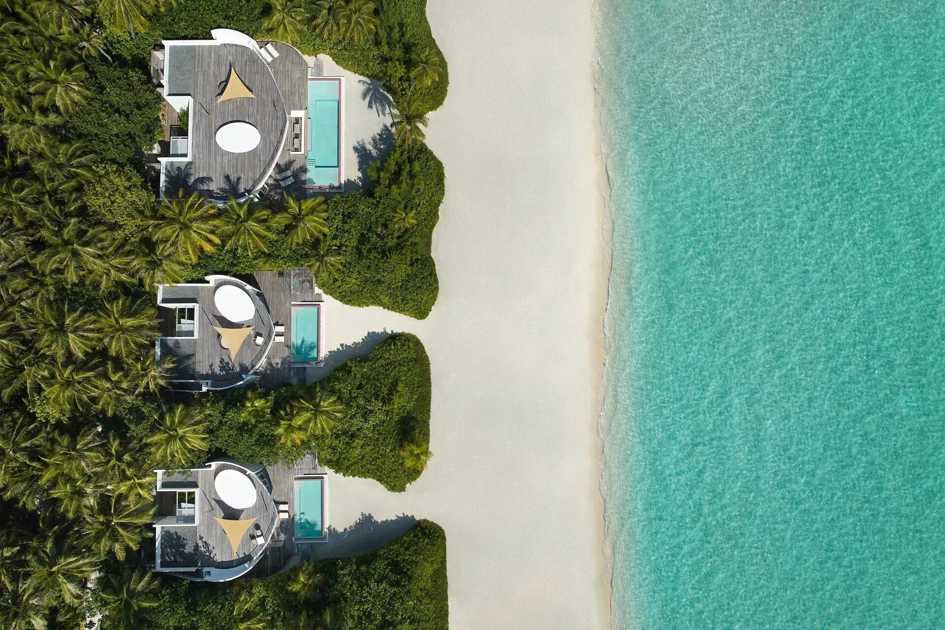 Aerial view of three One Bedroom Beach Villas at Jumeirah Olhahali, circular roof terraces and private pools set among palms beside the beach