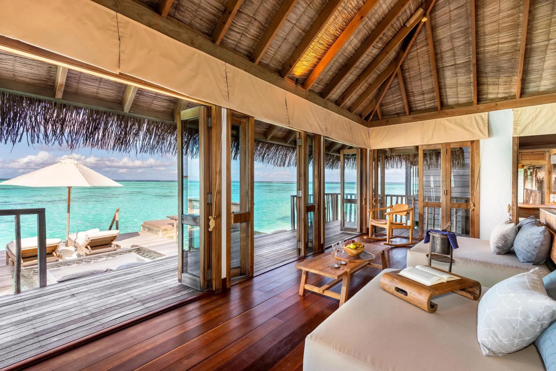 The air-conditioned living room of a Residence villa at Gili Lankanfushi, with two daybeds and a dining table