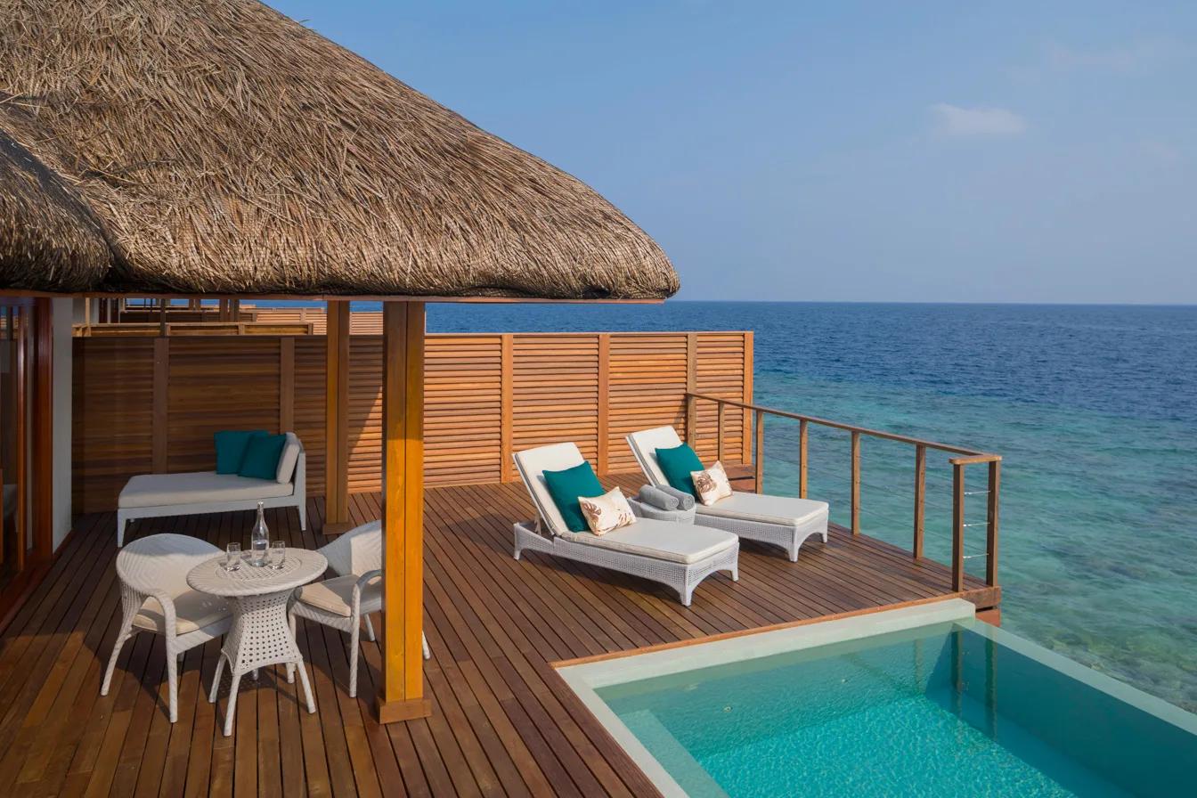 The private pool deck of a Waterfront Pool Villa at Dusit Thani Maldives, sun loungers and the open lagoon beyond