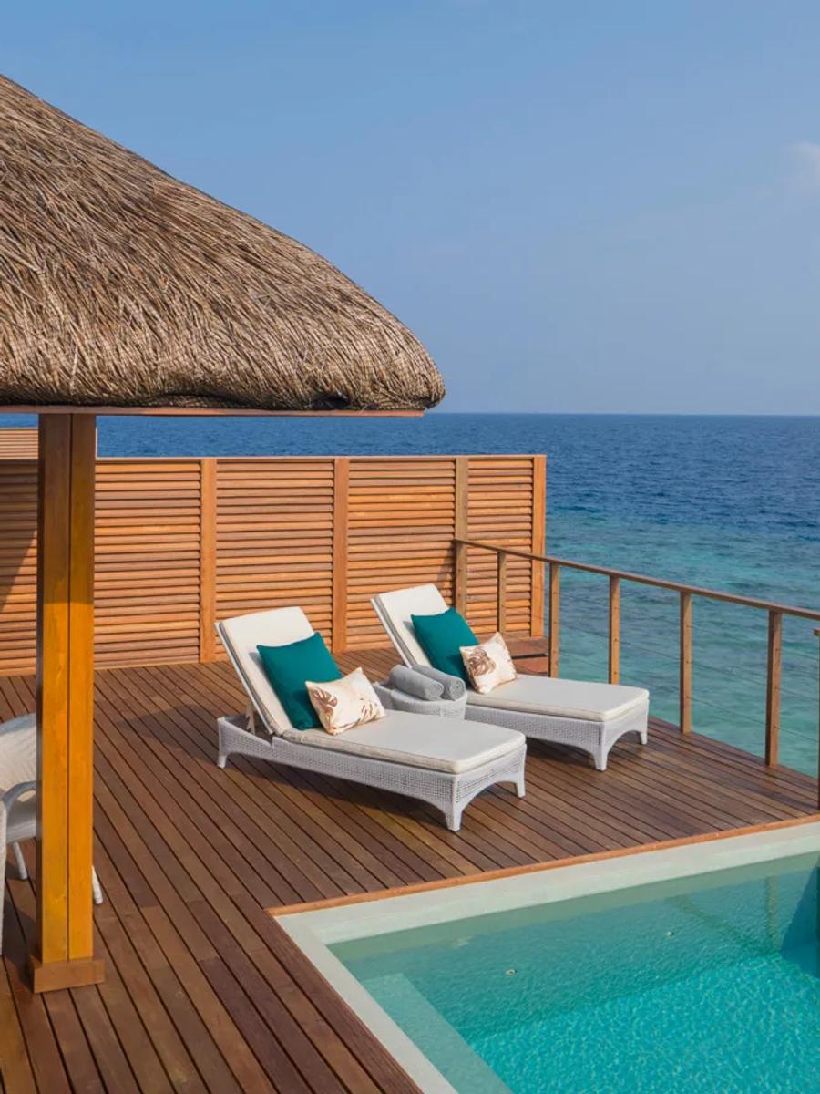 The private pool deck of a Waterfront Pool Villa at Dusit Thani Maldives, sun loungers and the open lagoon beyond