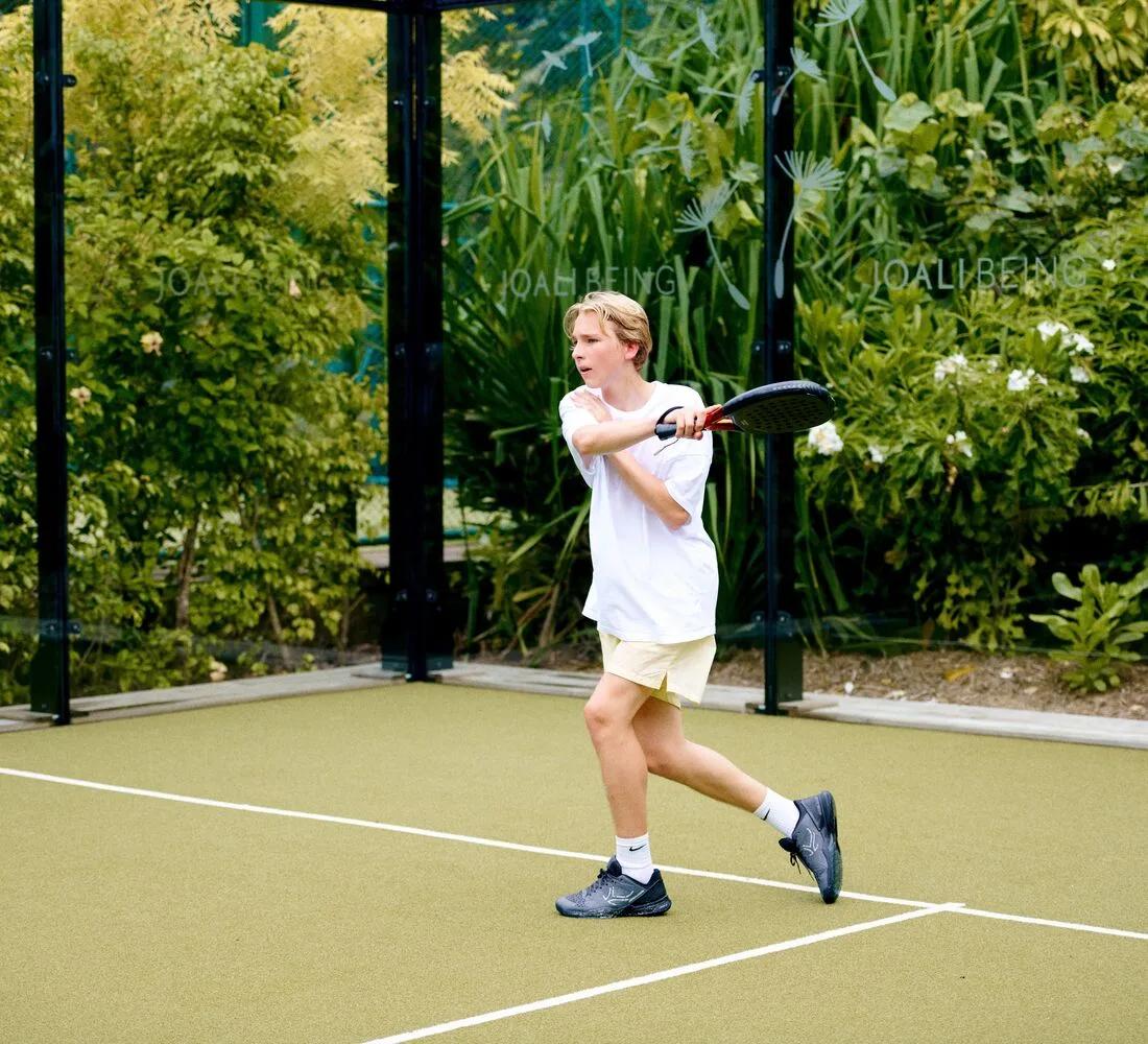 A guest returns a shot on one of Joali Being's padel courts