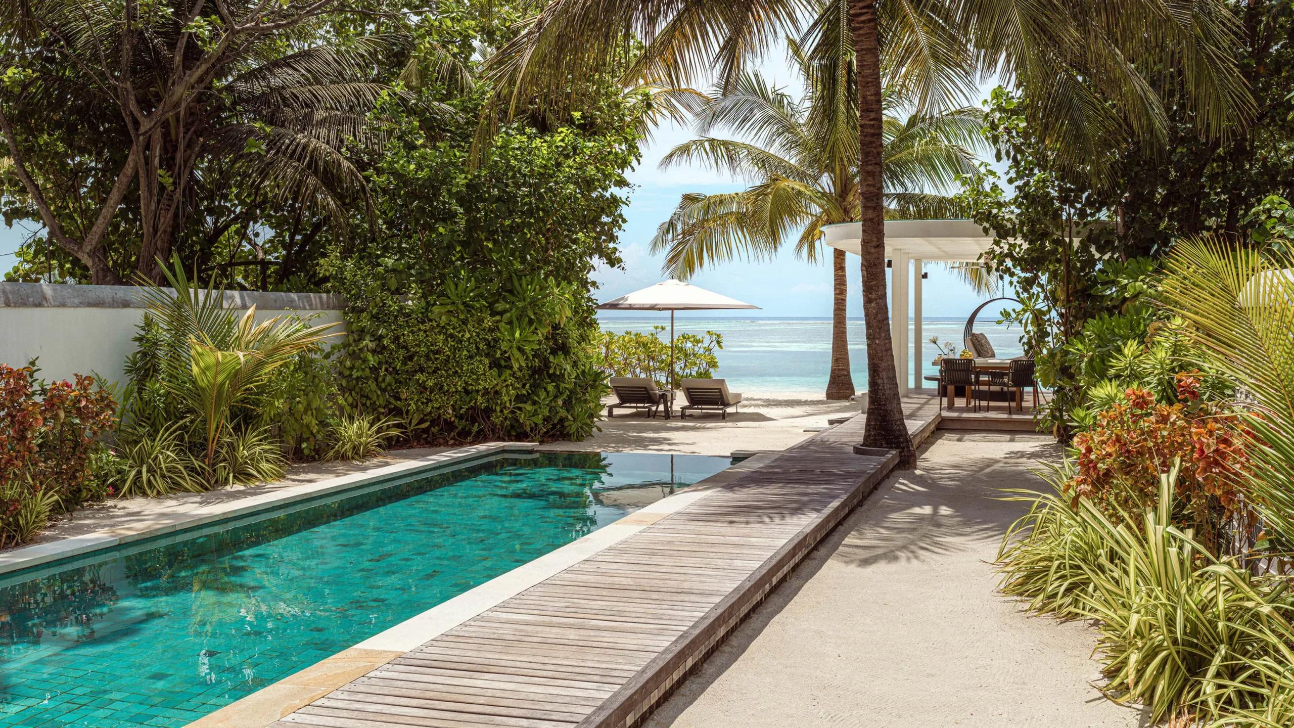A Sunrise Beach Villa's private pool and sun loungers, screened by garden