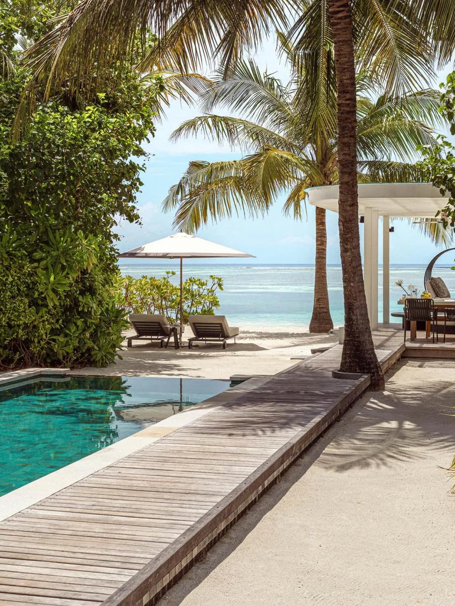 A Sunrise Beach Villa's private pool and sun loungers, screened by garden