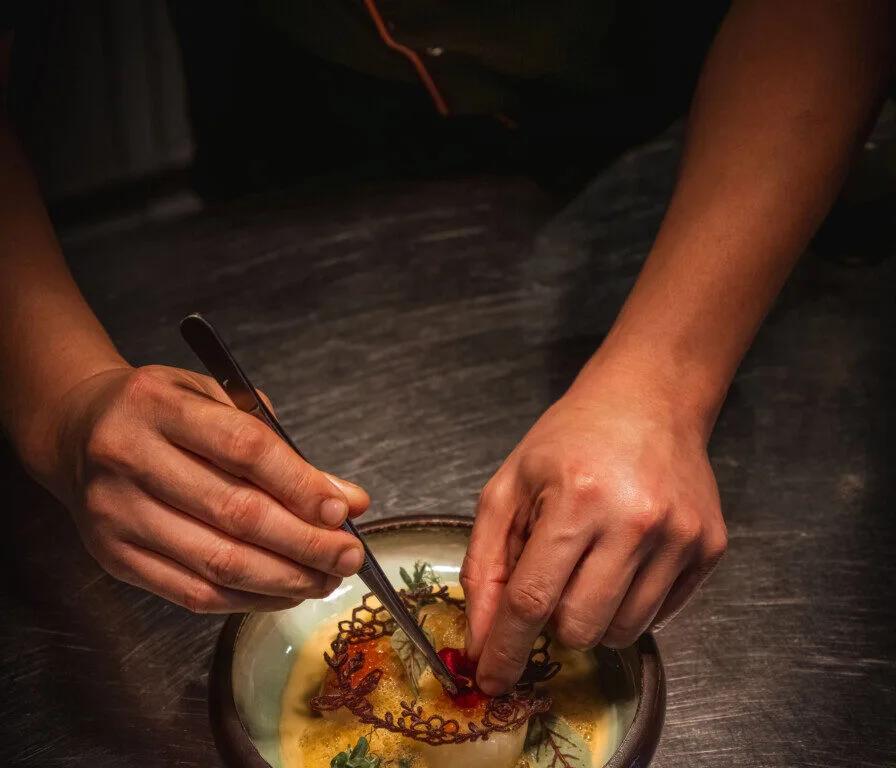 A chef's hands plating a dish at The Lighthouse restaurant
