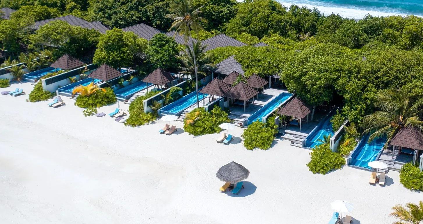 An aerial view along a row of beachfront pool villas and sun loungers, from the resort's Kanifushi Grand Pool Villa photo set