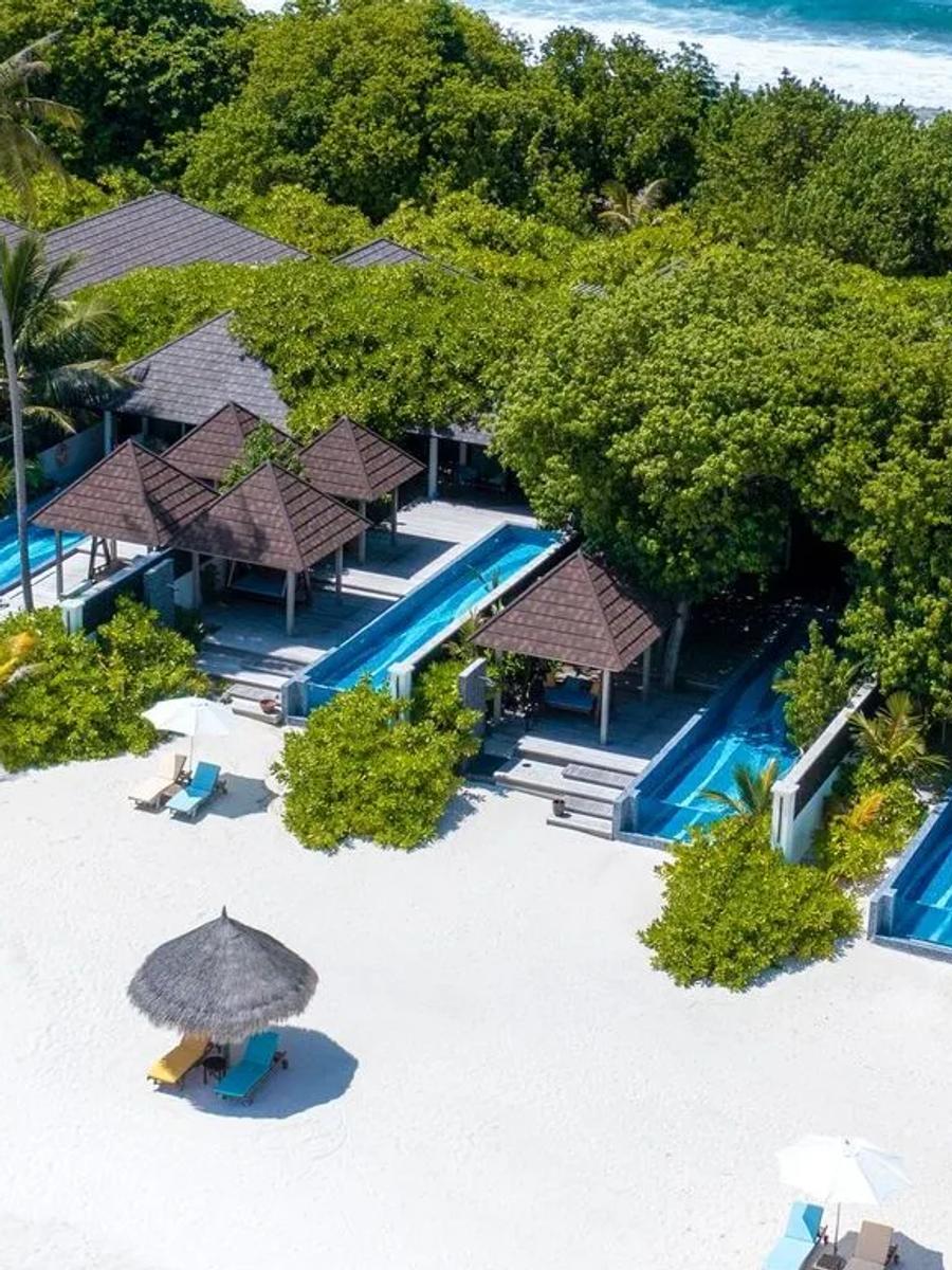 An aerial view along a row of beachfront pool villas and sun loungers, from the resort's Kanifushi Grand Pool Villa photo set