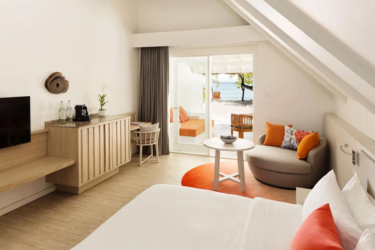 Interior of a Beach Pavilion bedroom, with sliding doors open to a beachfront terrace and the sea beyond