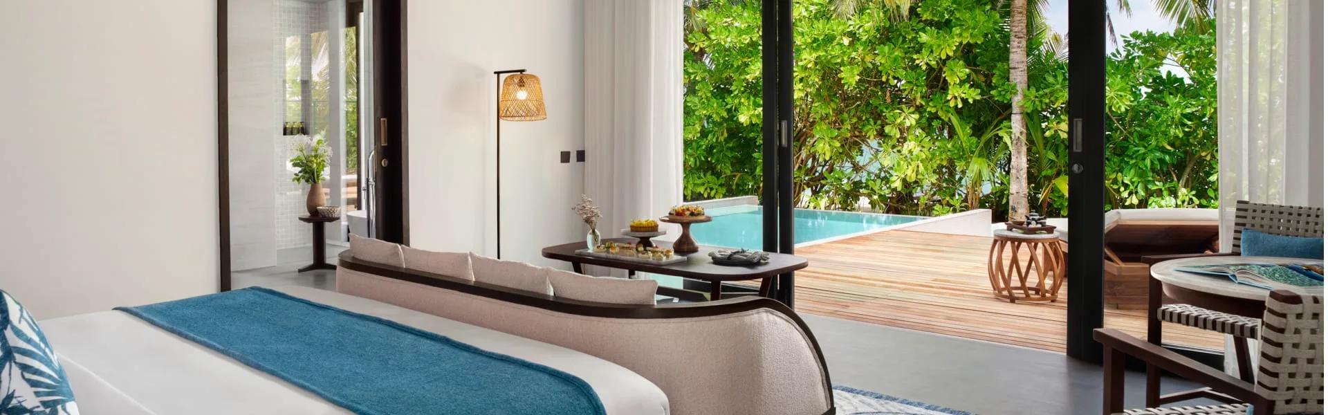 Beach Pool Villa bedroom opening onto its private pool and deck through palm trees
