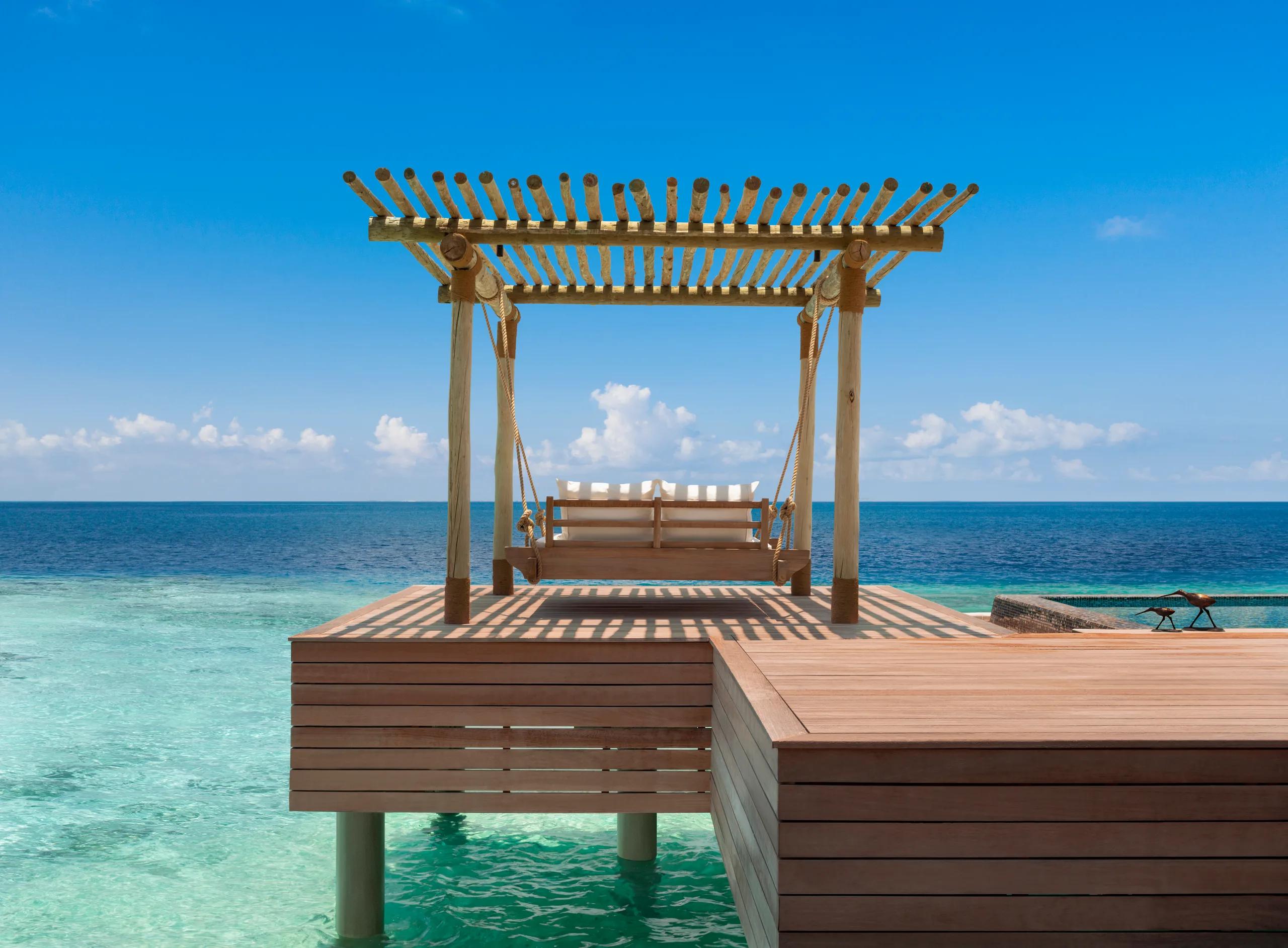 A swing bed positioned over the water at a Reef Villa, Waldorf Astoria Maldives Ithaafushi — the Two Queen Bedded Reef Villa has no dedicated published photo, so this sibling reef-villa image stands in here
