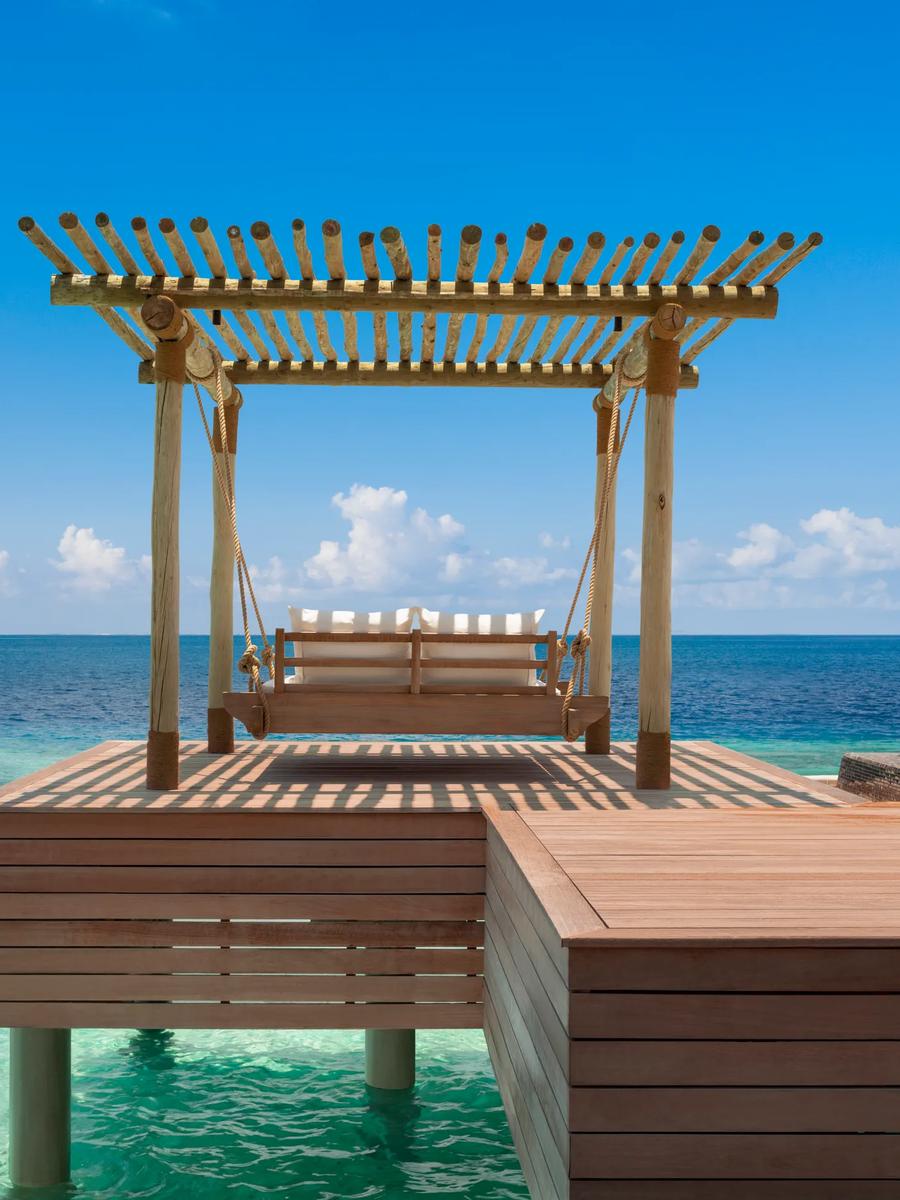 A swing bed positioned over the water at a Reef Villa, Waldorf Astoria Maldives Ithaafushi — the Two Queen Bedded Reef Villa has no dedicated published photo, so this sibling reef-villa image stands in here