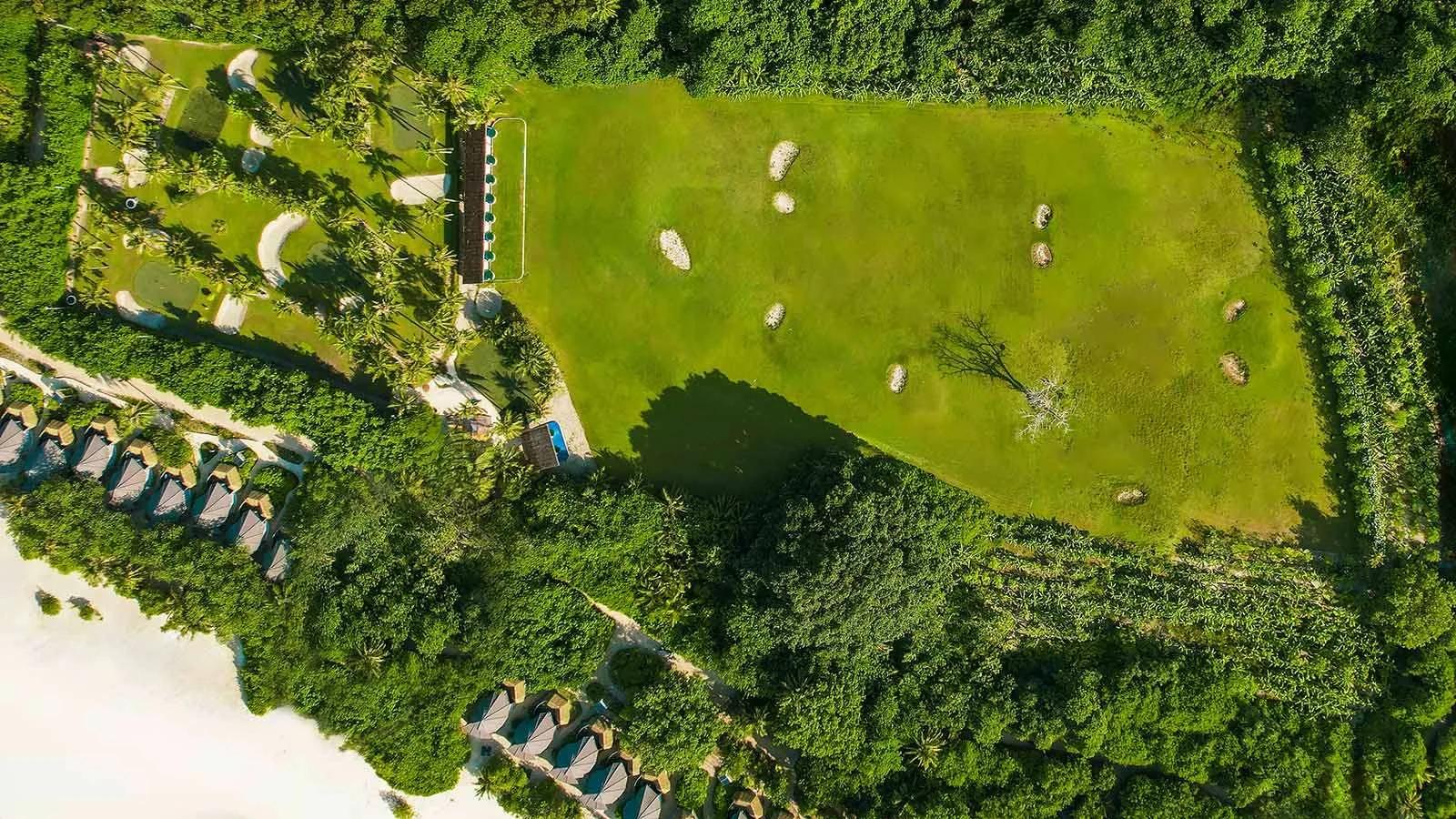 Aerial view of Kuredu's six-hole pitch-and-putt golf course and driving range, bordered by jungle