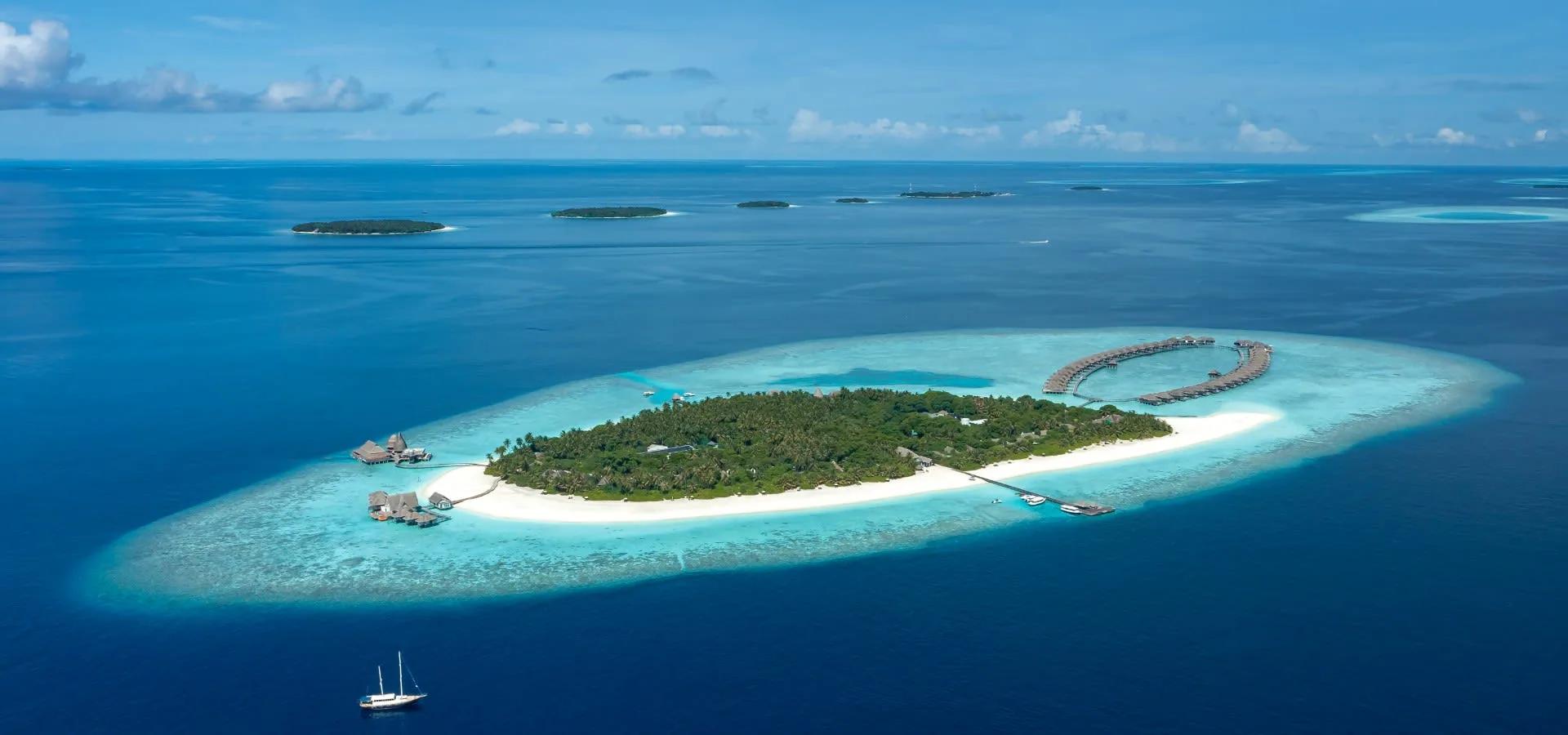 Aerial view of Anantara Kihavah Maldives Villas, overwater villas ringing Huravalhi Island's lagoon in Baa Atoll