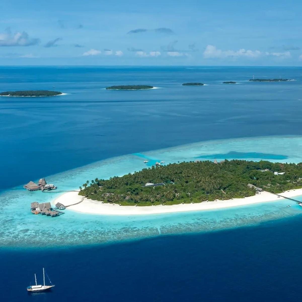 Aerial view of Anantara Kihavah Maldives Villas, overwater villas ringing Huravalhi Island's lagoon in Baa Atoll