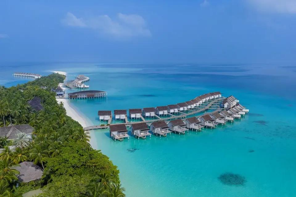 Aerial view of the Deluxe Water Villa jetty extending over the lagoon, beachfront pool villas visible on the island behind