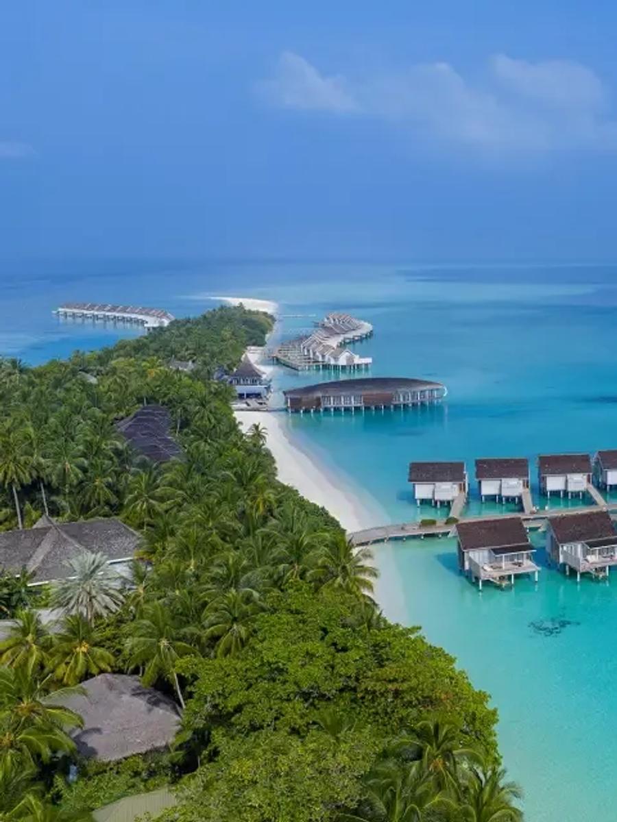 Aerial view of the Deluxe Water Villa jetty extending over the lagoon, beachfront pool villas visible on the island behind