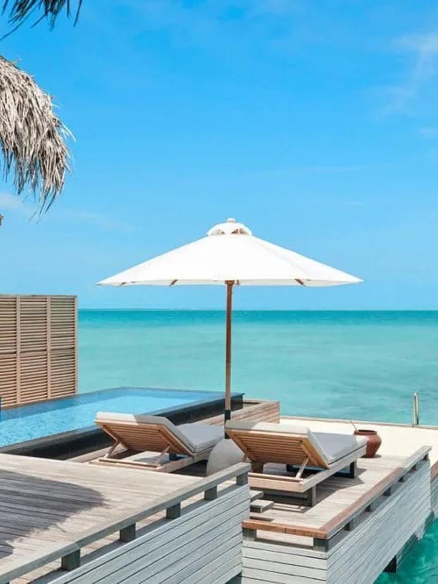 Overwater deck with a private pool, a shaded daybed with a hanging chair, and open lagoon views