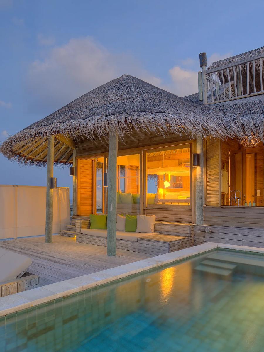 An Ocean Water Villa with Pool lit up at dusk, its private pool and deck extending over the lagoon