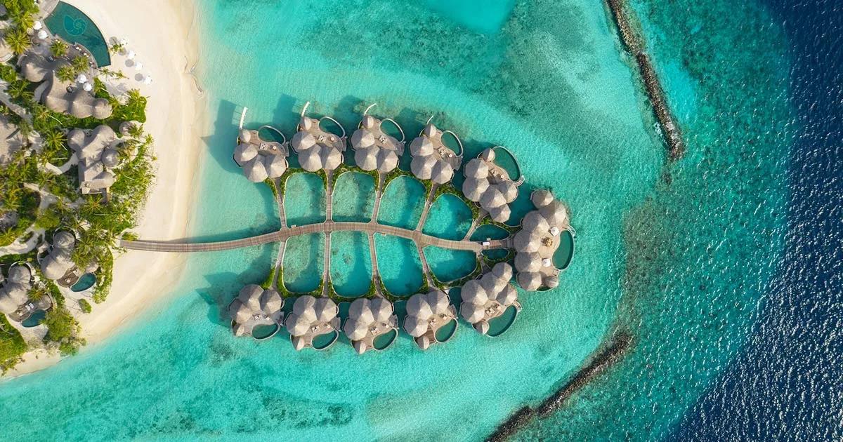 Aerial view of Nautilus Maldives' overwater Ocean Houses, arranged along a curved jetty over the Baa Atoll lagoon.