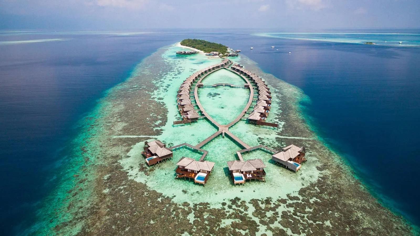 Aerial view of Lily Beach Resort & Spa on Huvahendhoo, South Ari Atoll, its villa rows and lagoon jetty framed by reef