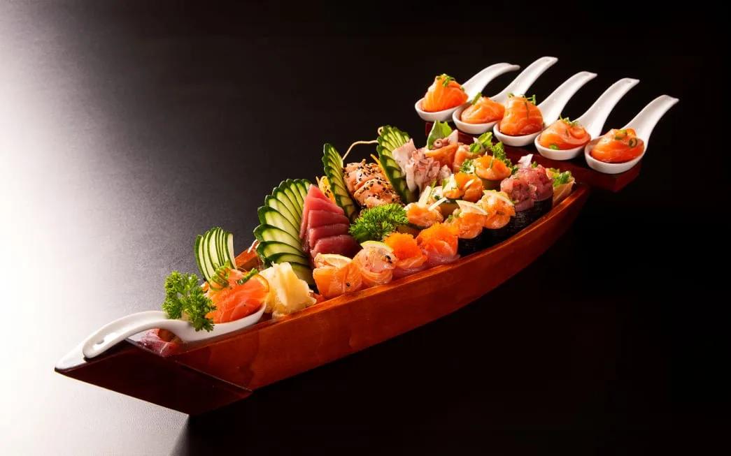 A wooden sushi boat with sashimi, nigiri and rolls at Origami