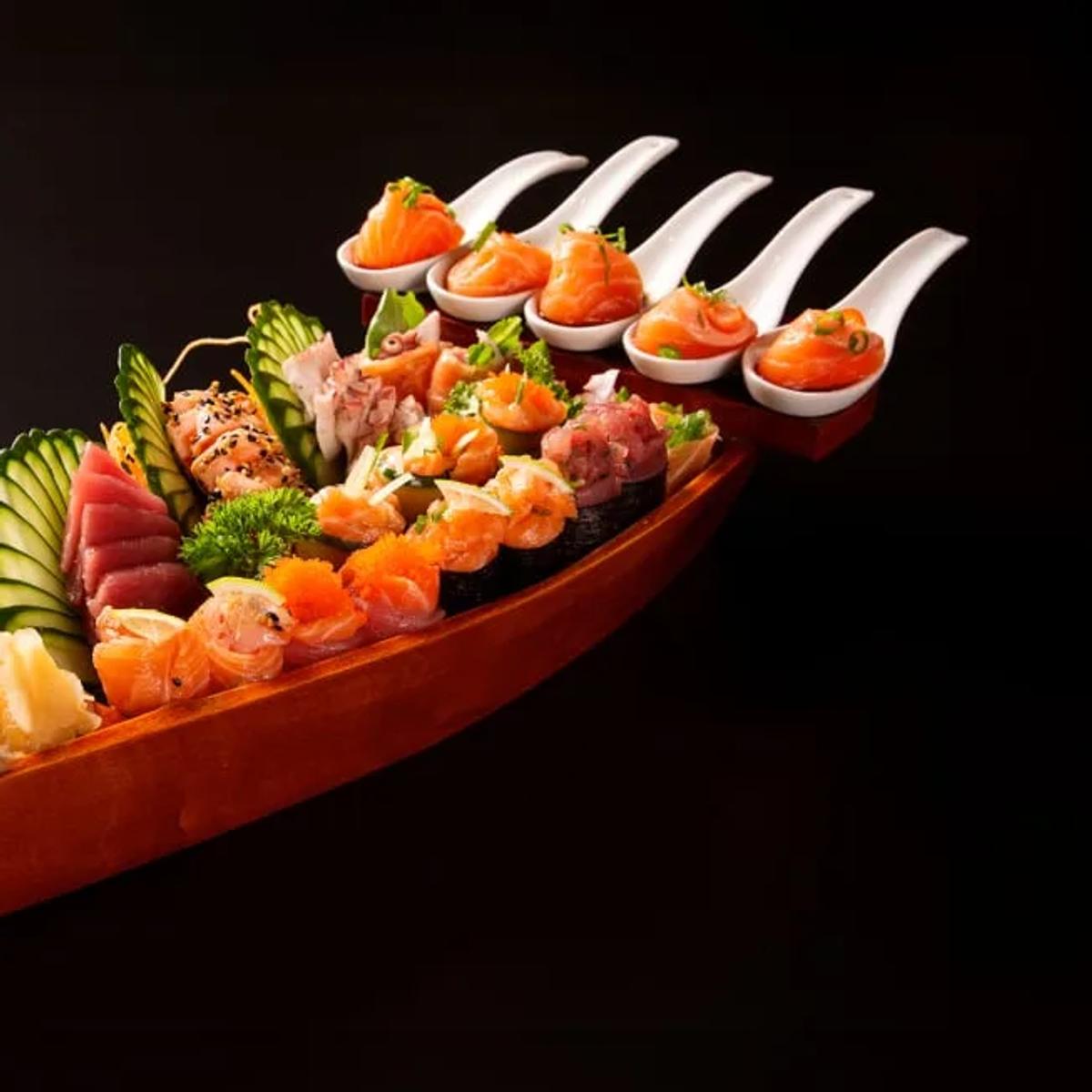 A wooden sushi boat with sashimi, nigiri and rolls at Origami