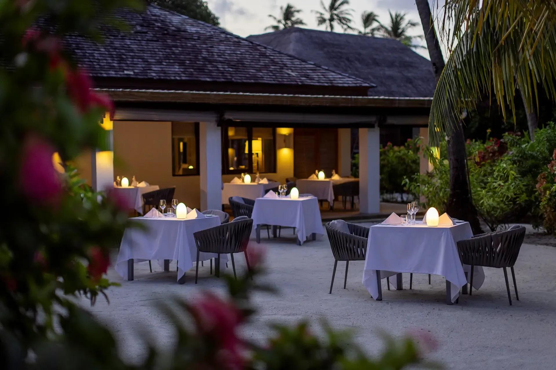 Candlelit tables set for dinner on Etesian's garden terrace at dusk
