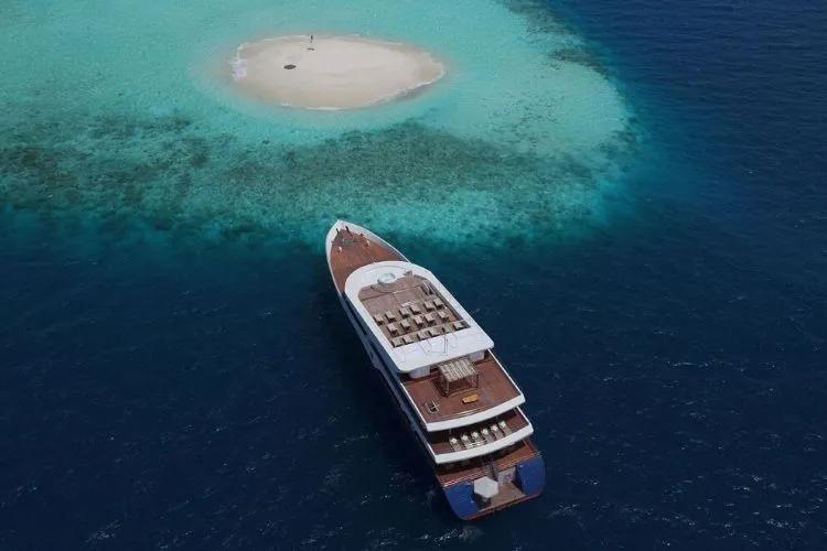 A charter yacht cruising Maldivian waters beyond the shoreline