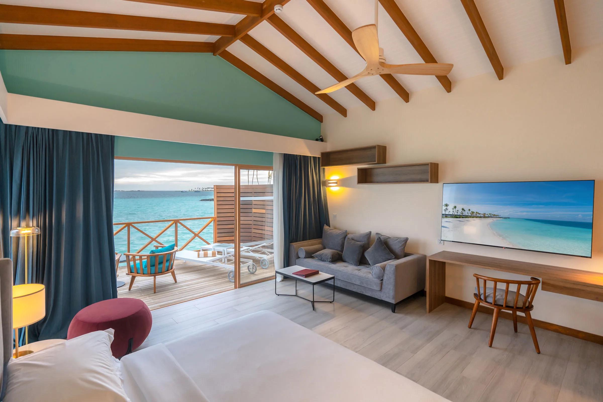 A Lagoon Villa's living room, sliding glass doors open onto its deck above the lagoon
