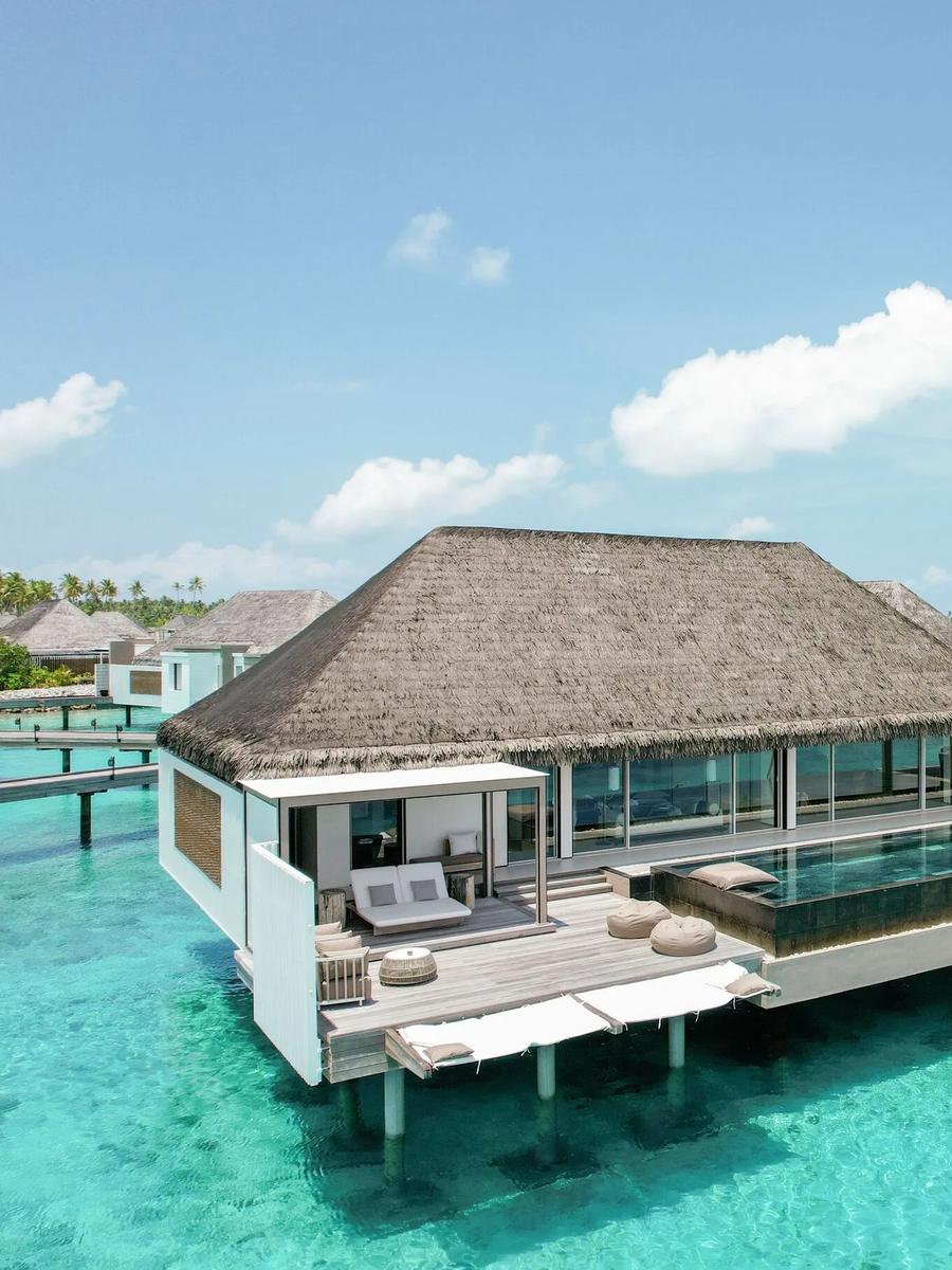 The Horizon Villa's infinity pool extending toward the open lagoon, thatched pavilion and daybeds on the deck