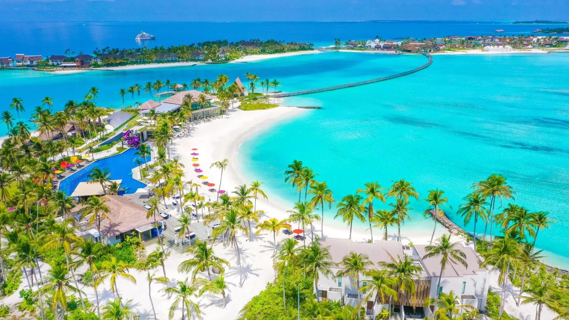 Hard Rock Hotel Maldives seen from above, the main pool and beach with the footbridge to The Marina @ CROSSROADS beyond