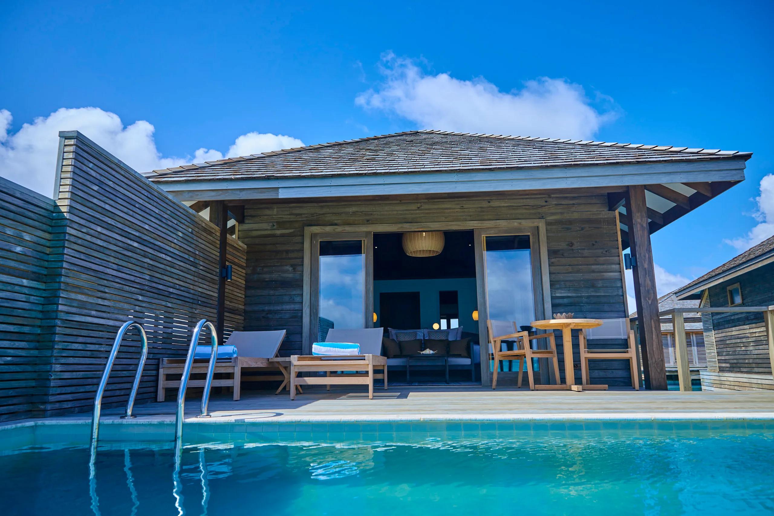 The exterior of an overwater Water Pool Villa at Jawakara, timber-slat walls and a private infinity pool beside the deck ladder into the lagoon