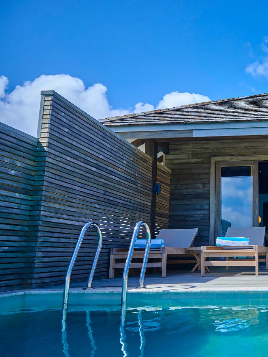 The exterior of an overwater Water Pool Villa at Jawakara, timber-slat walls and a private infinity pool beside the deck ladder into the lagoon