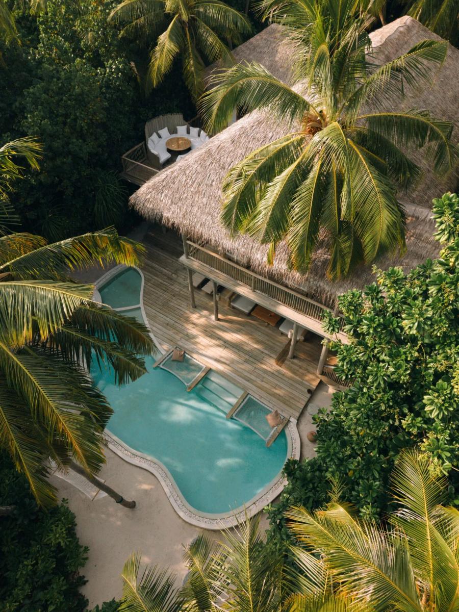 An aerial view of a Soneva Fushi Villa Suite's free-form pool and circular daybed nook, framed by jungle canopy — representative of the resort's four-bedroom villa suites