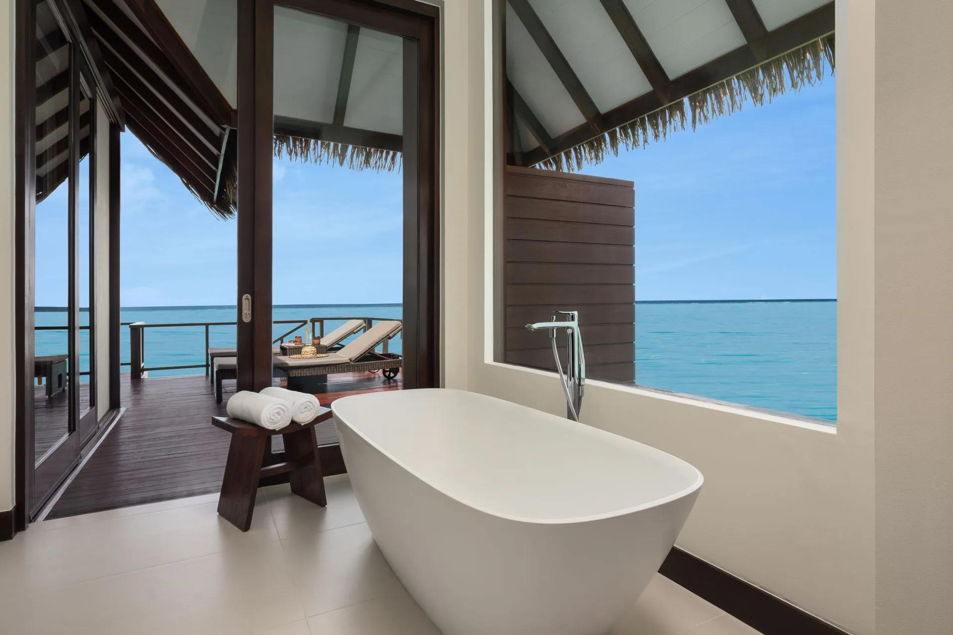 The overwater bathroom of an Ocean Villa at Heritance Aarah, with its private sun deck visible through the doorway