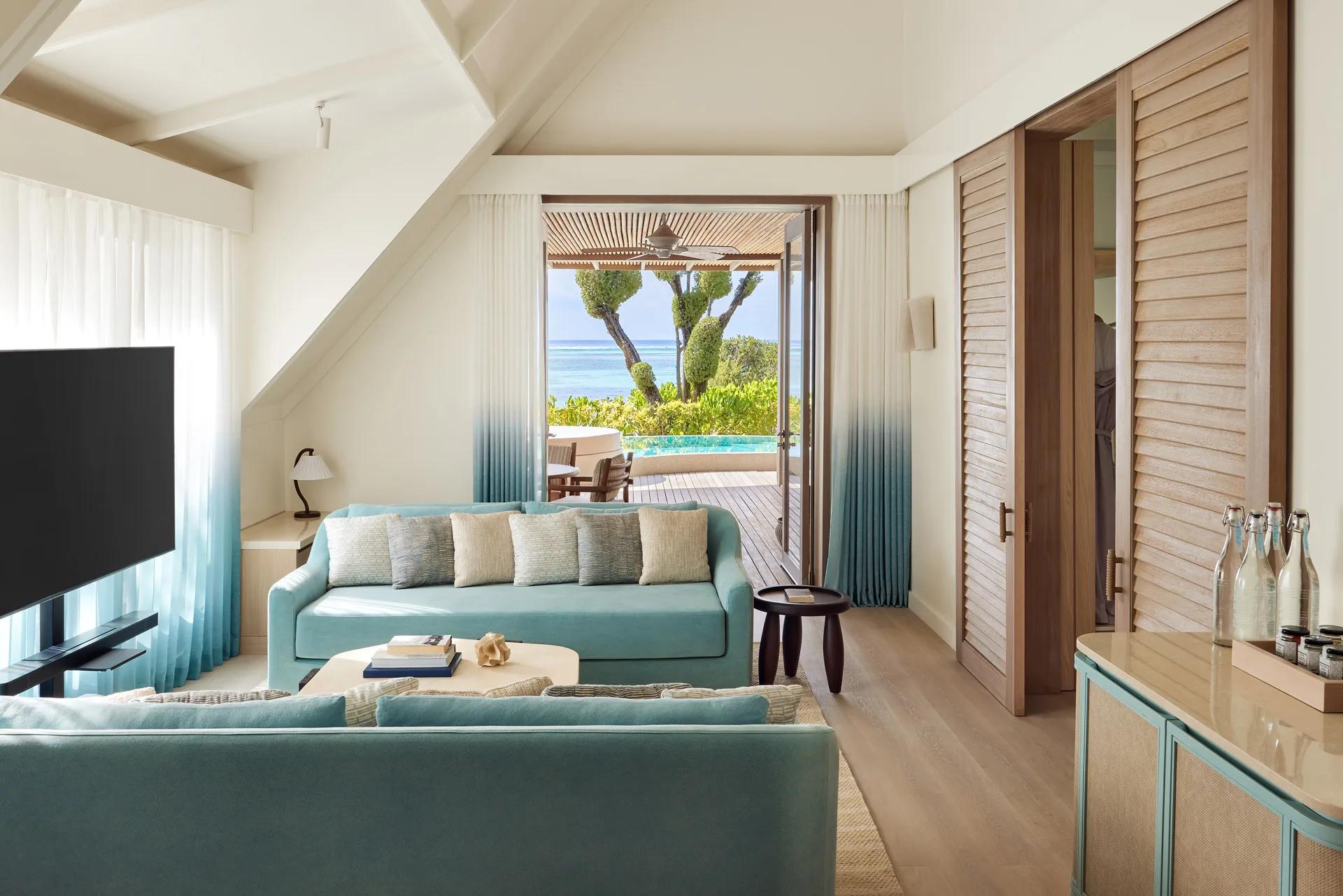 Interior lounge of a Temptation Beach Pool Villa, with glass doors open to its private pool terrace