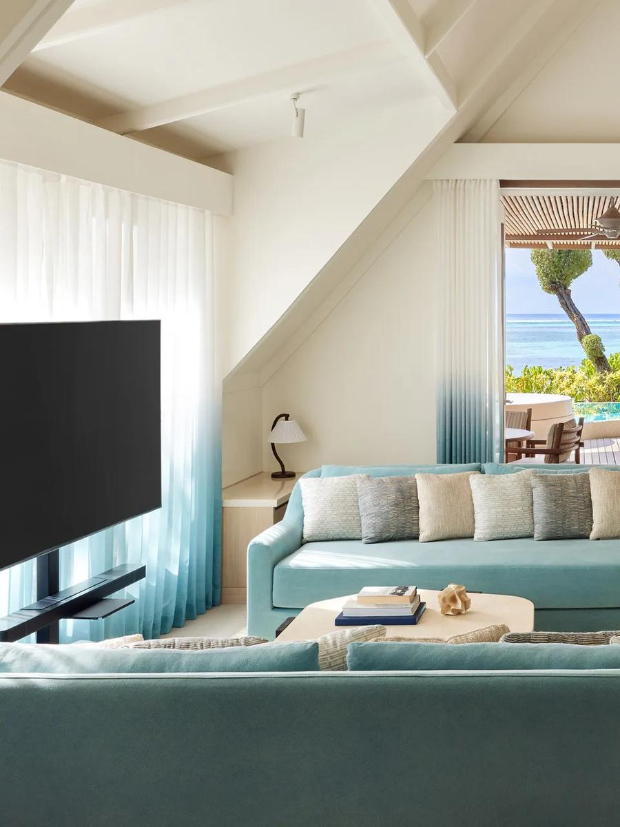 Interior lounge of a Temptation Beach Pool Villa, with glass doors open to its private pool terrace