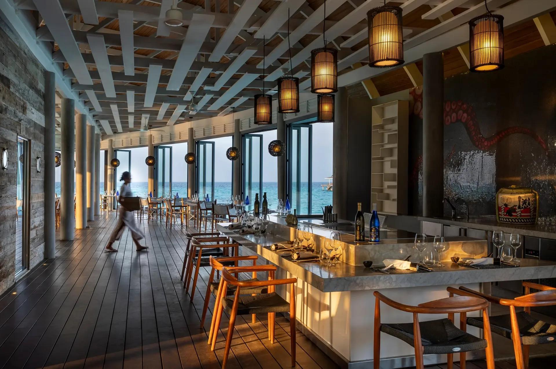 Kobe's overwater teppanyaki counter set with lanterns overhead, tables looking out to the ocean at dusk