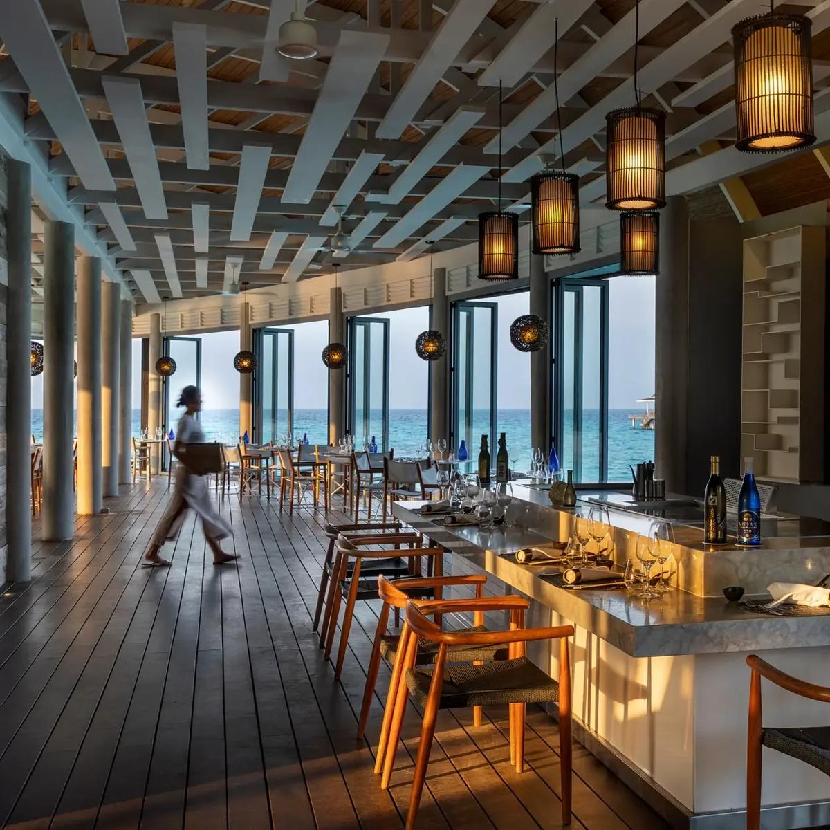 Kobe's overwater teppanyaki counter set with lanterns overhead, tables looking out to the ocean at dusk