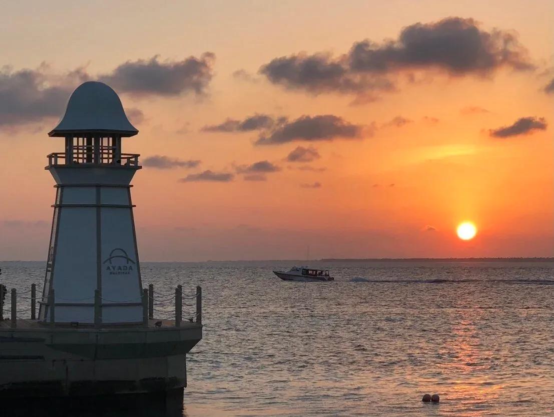 The Ayada beacon at the end of the jetty, a speedboat passing at sunset