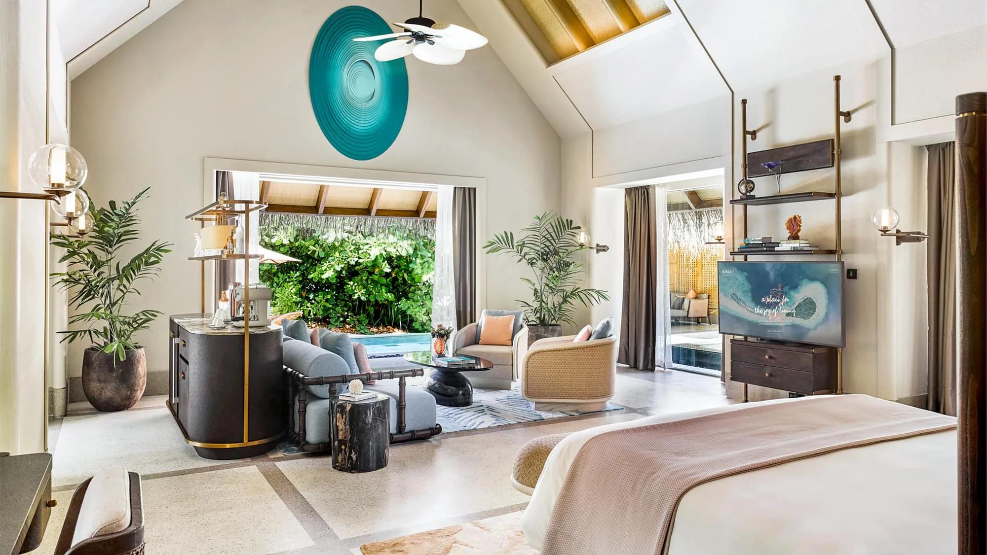 The living room of a Beach Villa with Pool, with a teal art piece above the bar and the private pool visible through the open wall