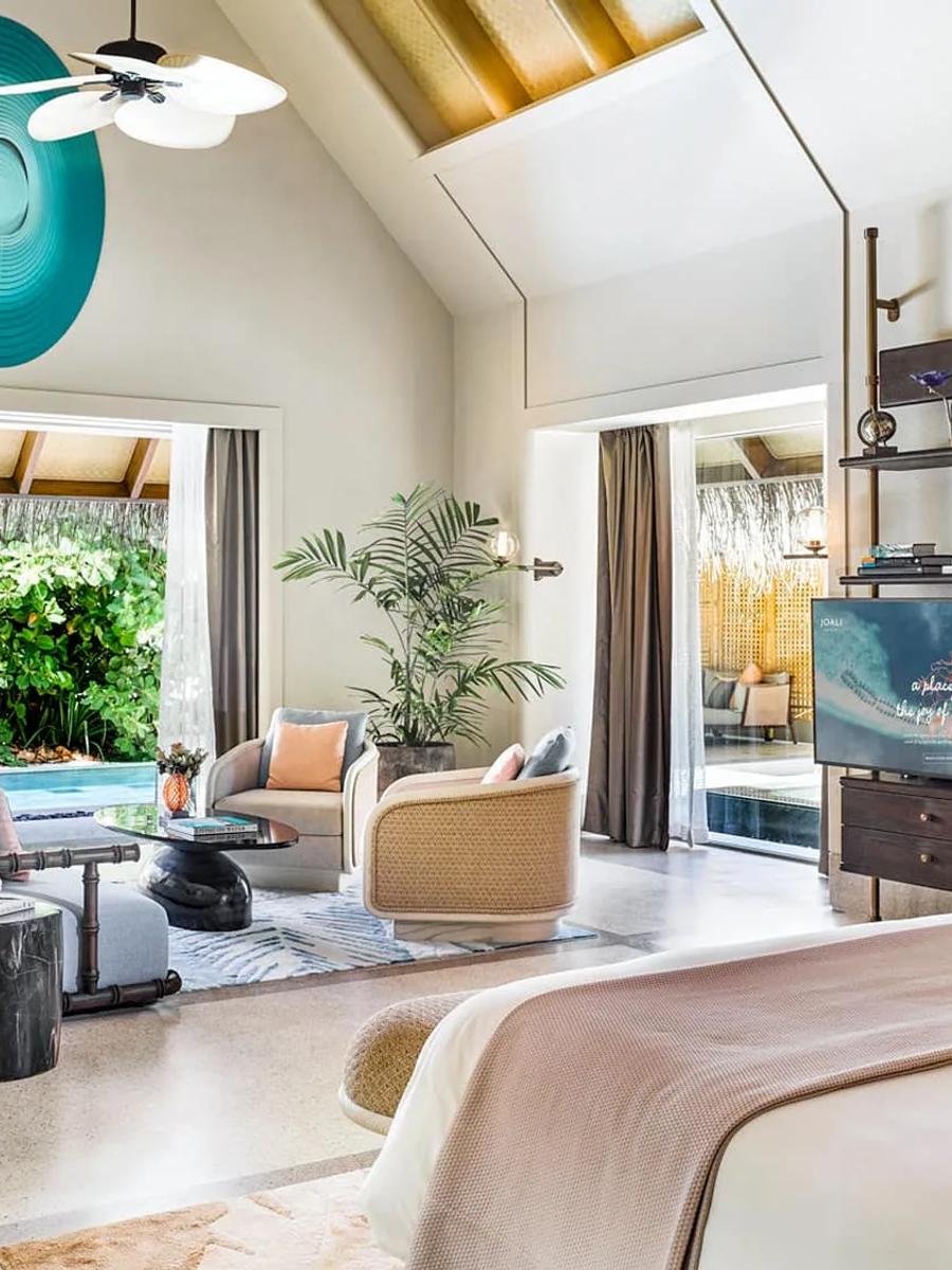 The living room of a Beach Villa with Pool, with a teal art piece above the bar and the private pool visible through the open wall